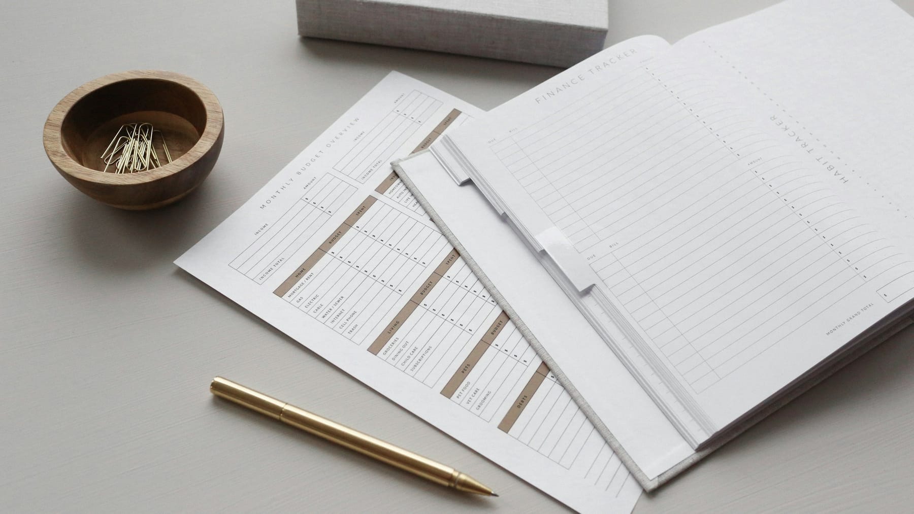 Printed forms laid out on a plain desk beside a pen.